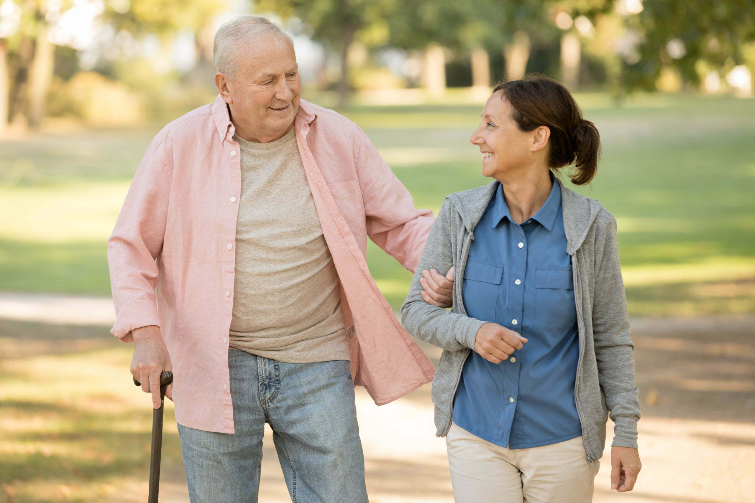 senior resident and caregiver go walking outdoors