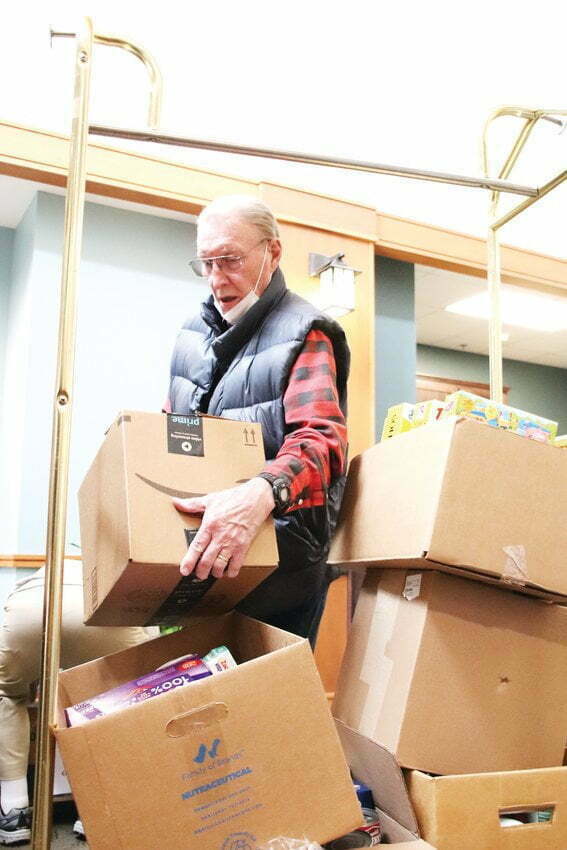 Don Folsom, an 80-year-old resident of Holly Creek Retirement Community, helps load boxes in the Holly Creek lobby at the end of a food drive put on by residents.