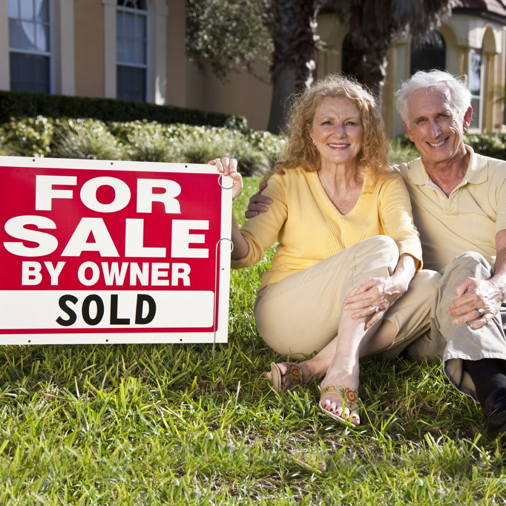 couple moving with for sale sign