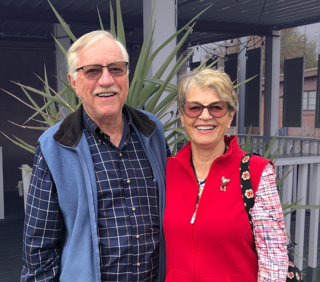 Jim and Pat Neel smile outside in front of cactus.