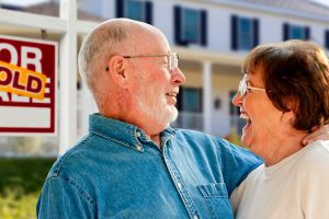 couple moving with for sale sign