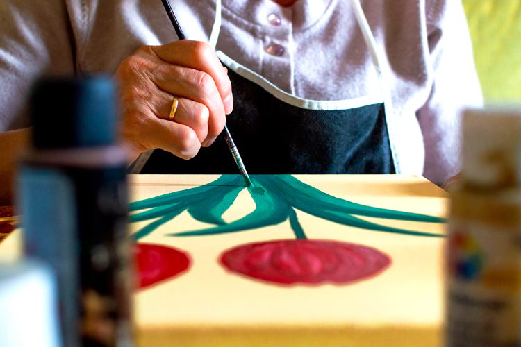 closeup of hand painting a flower on canvas
